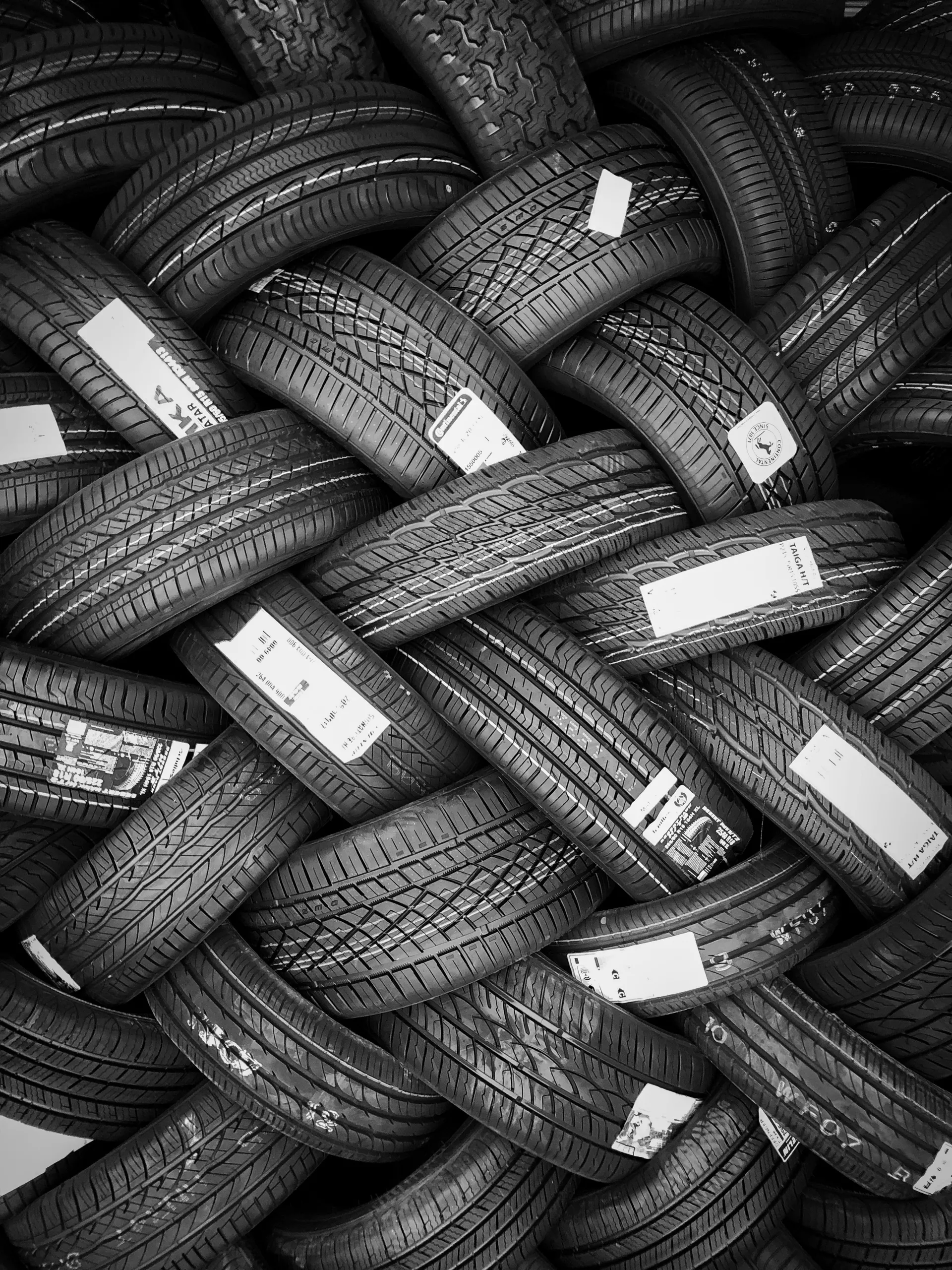 Pila de neumáticos dispuestos en un patrón trenzado, imagen en blanco y negro